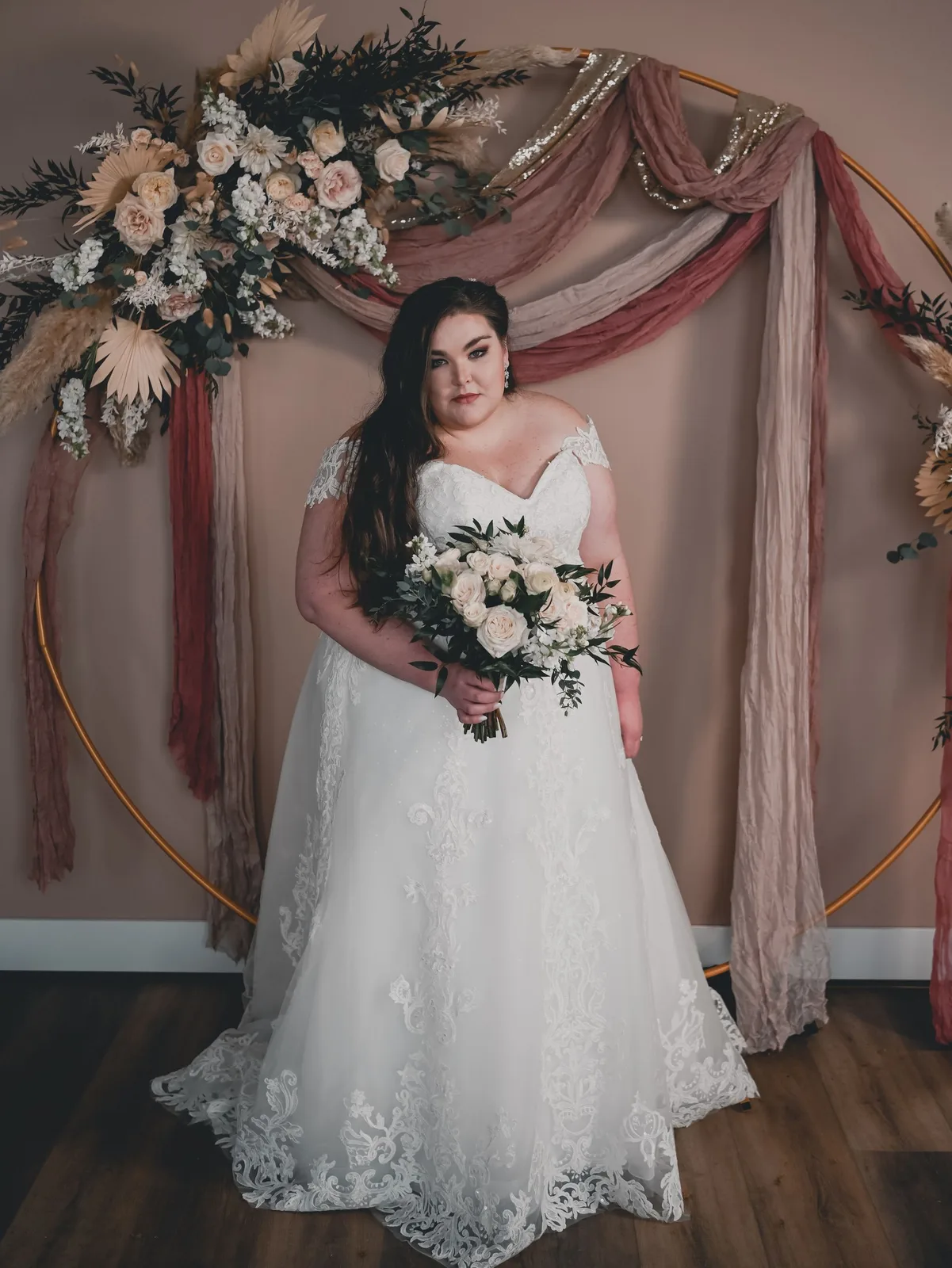 Bride in a romantic gown against a soft blush backdrop