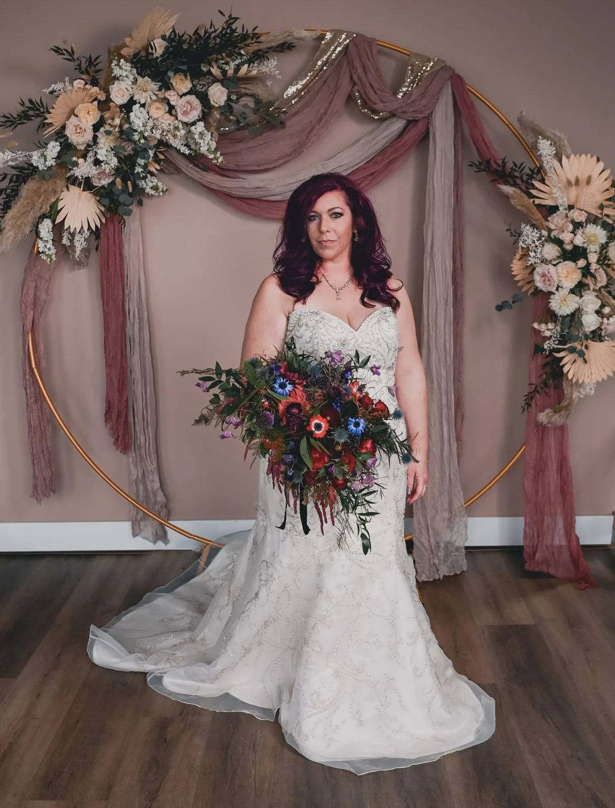 Bride holding a bouquet against a blush backdrop