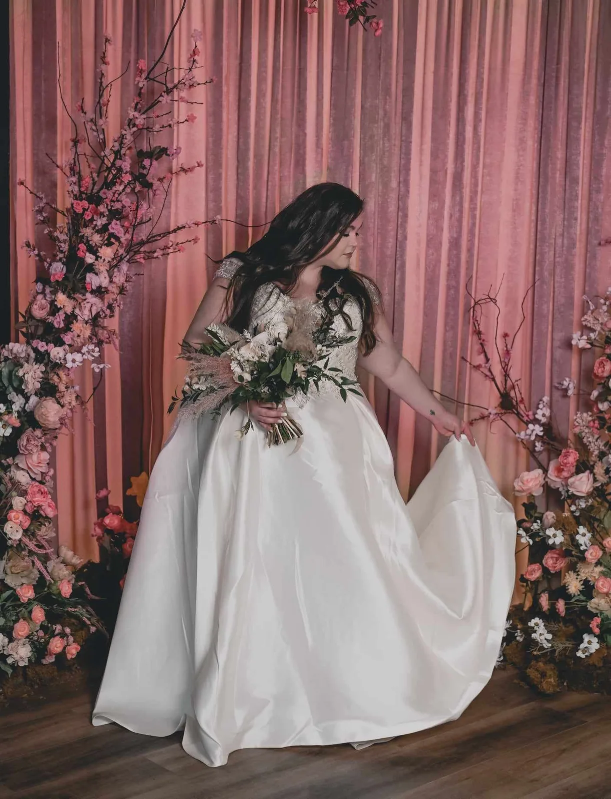 Bride in a gown against a draped blush backdrop